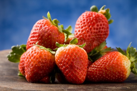 photo of delicious red strawberries on wooden table in front of a blue backgroundの写真素材