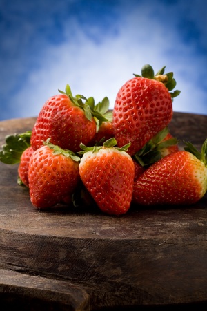 photo of delicious red strawberries on wooden table in front of a blue backgroundの写真素材