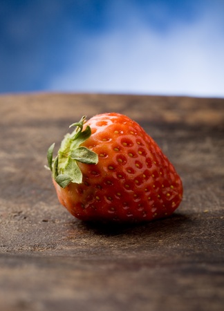 photo of delicious red strawberries on wooden table in front of a blue backgroundの写真素材