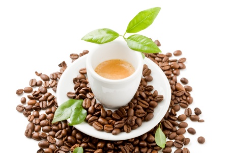 photo of espresso cup over coffee beans with green leaves on white isolated backgroundの写真素材