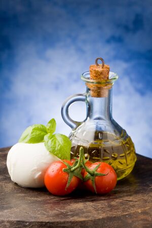 photo of tomato mozzarella on wooden table in front of blue background の写真素材