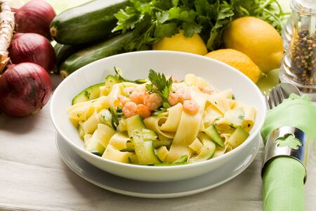 photo of delicious italian pasta with zucchini and shrimpsの写真素材