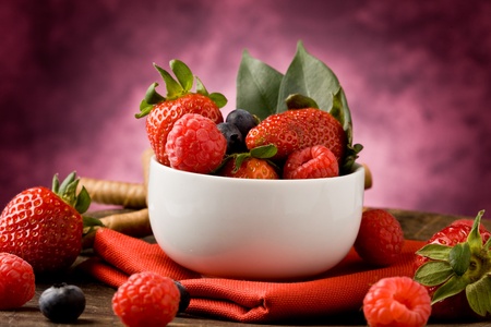 photo of berries inside a white bowl on wooden tableの写真素材