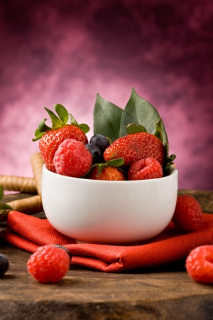 photo of berries inside a white bowl on wooden tableの写真素材