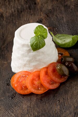 photo of delicious ricotta cheese with tomatoes on wooden table with basil の写真素材