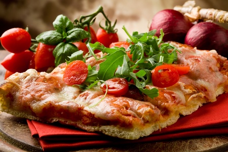 sliced pizza with arugula and cherry tomatoes on wooden tableの写真素材