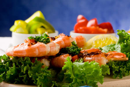 photo of delicious grilled prawns over lettuce bed with peperoni over blue backgroundの写真素材