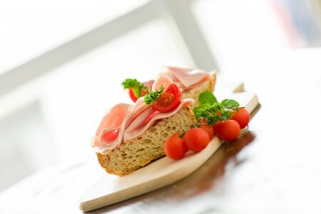 delicicious ham tomato sandwich with fresh parsley on wooden table with day light illuminationの写真素材