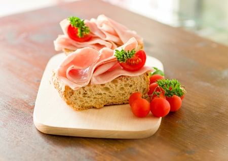 delicicious ham tomato sandwich with fresh parsley on wooden table with day light illuminationの写真素材