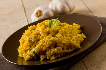 delicious risotto with saffron on wooden table with garlic and napkinの写真素材