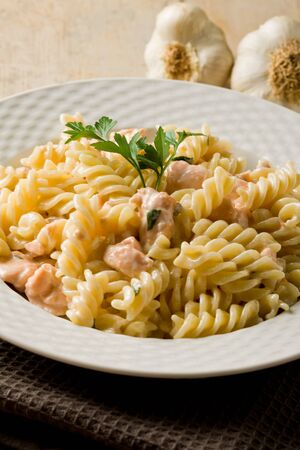 photo of delicious pasta with salmon and cream on wooden backgroundの写真素材