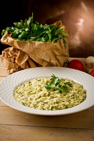 photo of delicious risotto dish with herbs on wooden tableの写真素材