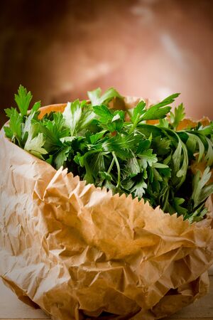 photo of fresh parsley inside a paper bag on wooden tableの写真素材
