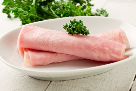 photo of delicious rolled ham with parsley on wooden tableの写真素材