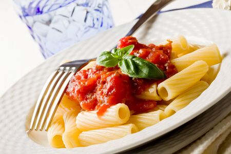 photo of delicious pasta with basil and tomato sauce on white wooden tableの写真素材