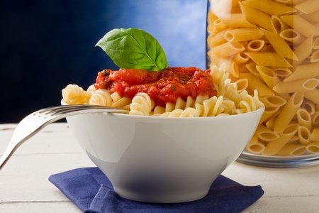 photo of delicious pasta with tomato sauce on blue backgroundの写真素材