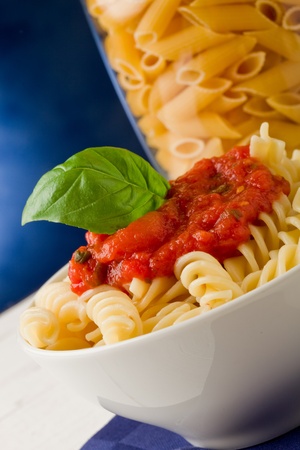 photo of delicious pasta with tomato sauce on blue backgroundの写真素材
