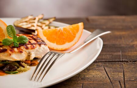 delicious grilled chicken breast with orange on ratatouille bedの写真素材