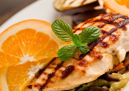 delicious grilled chicken breast with orange on ratatouille bedの写真素材