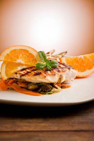 delicious grilled chicken breast with orange on ratatouille bedの写真素材