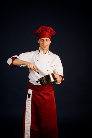 photo of young male chef with a pot in his hand who is cookingの写真素材