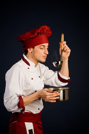 photo of young chef with pot in his hend tasting the food smellの写真素材