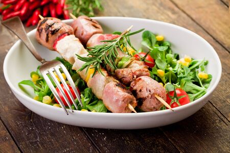 delicious broiled meat skewers on wooden table with saladの写真素材