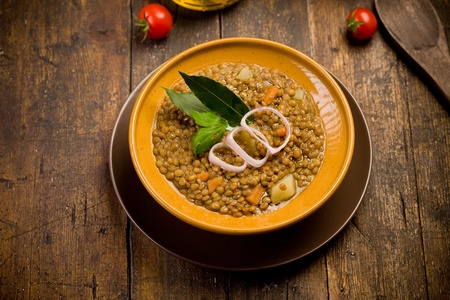 fresh homemade lentils soup with onions and cherry tomatoes on wooden tableの写真素材