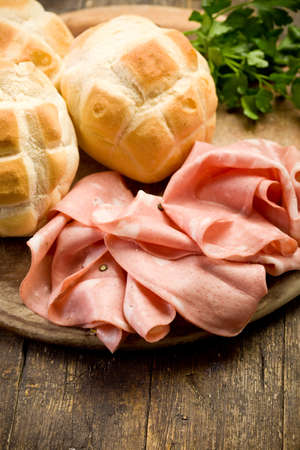 Sliced soft mortadella sausage on wooden table with breadの写真素材