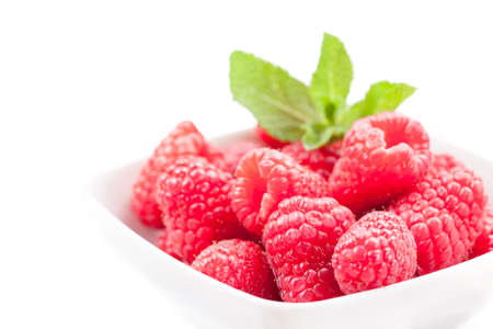photo of fresh raspberries inside a bowl with mint on white backgroundの写真素材