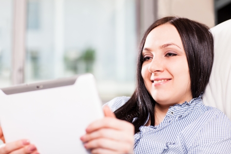 Beautiful woman at home is smiling while videocalling with a tabletの写真素材