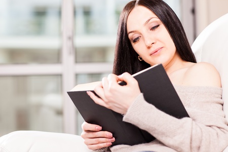 Beautiful woman at home is reading a book の写真素材