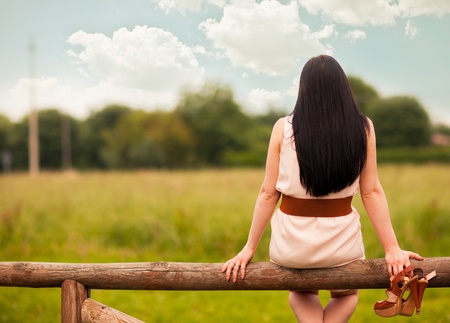 photo of young woman looking at the clouds while sitting on a hurdleの写真素材