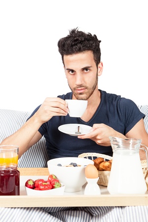 photo of adult man having breakfast in the bed on white backgroundの写真素材