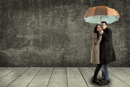 young couple searching protection under an umbrellaの写真素材