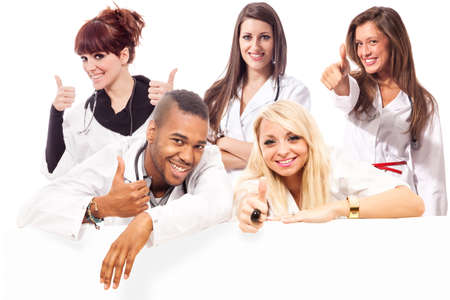 Young medical students smiling making positive thumb gesture in front of a message boardの写真素材