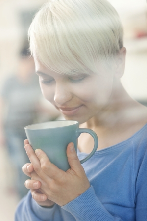 photo of attractive woman enjoying her coffee behind a windowの写真素材