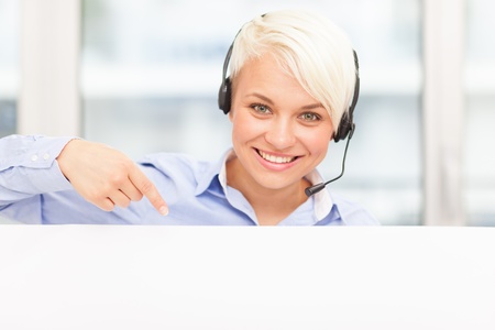 female support assistant is smiling while indicating a banner with her fingerの写真素材