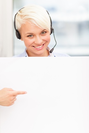 female support assistant is smiling while indicating a banner with her fingerの写真素材