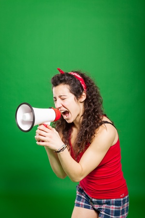 young woman screaming through megaphone over green backgroundの写真素材