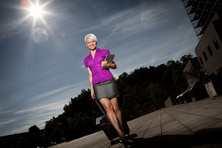 photo of attractive Businesswoman with trolley and tablet pc walking の写真素材