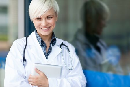 smiling attractive female doctor in front of a glass wallの写真素材