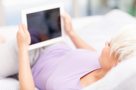 Photo of smiling woman with tablet pc in the bed の写真素材