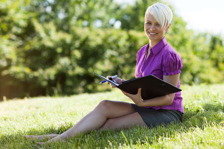 Photo of smiling blonde woman sitting in a parkの写真素材