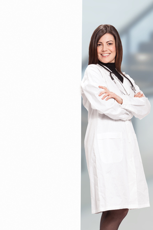 Photo of brunette smiling female doctor with message boardの写真素材
