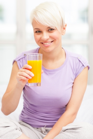 Photo of blonde woman having juice for breakfastの写真素材