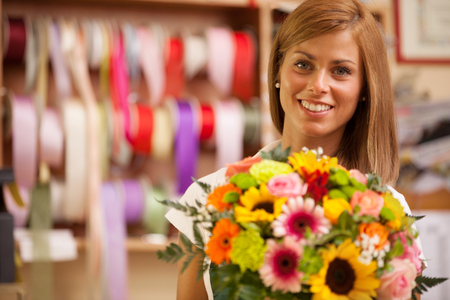 Beautiful smiling florist in her store with colorful bouquet の写真素材