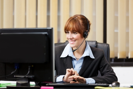 Brunette female support assistant working at the helpdeskの写真素材