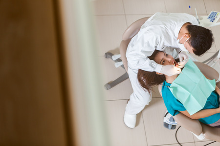 photo of male asian dentist doing his job on a young asian womanの写真素材