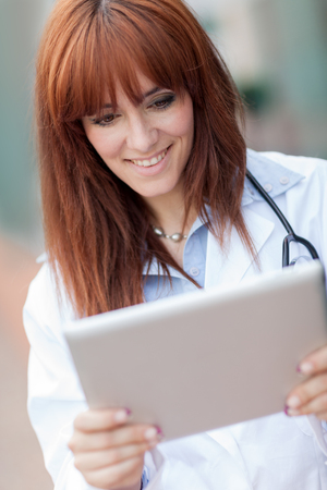photo of smiling female doctor looking at tablet pcの写真素材